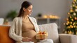 © ЮРИЙ ПОЗДНИКОВ - Pregnant woman in cozy living room holding gift, surrounded by warm holiday lights and festive decorations, creating a joyful atmosphere of anticipation