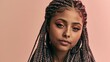 © Surachetsh - Portrait of an elegant young Black female model with braided hairstyle, pink makeup, hoop earrings, and calm expression isolated on a pink studio background.