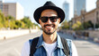 © gede - Smiling man with hat and sunglasses, wearing denim vest, standing outdoors in city, travel and lifestyle concept