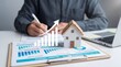 © MOHAMMADSAIFUL - Real estate agent analyzing house market growth with charts