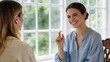 © Leo - Smiling woman explaining idea to friend during conversation, happy female gesturing hand while talking in bright room near window.