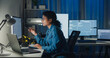 © tirachard - Young African American female programmer coding AI software on multiple screens in night office. Network security, cybersecurity, machine learning, working late, overtime, robotics automation concept.
