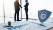© Kittiya - Two business professionals shake hands in an office with financial charts and a security shield icon symbolizing data protection.