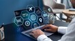 © alvi - Man using laptop with travel and logistics icons floating above screen in modern office setting