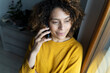 © Westend61 - Woman talking on the phone, looking out of window