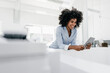 © Westend61 - Smiling young woman using tablet in office