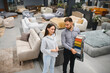 © Serhii - Female customer choosing sofa fabric at furniture store