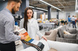 © Serhii - Client choosing upholstery fabric with sales consultant in furniture store