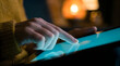 © MONJILA - Close up of person's hand with pointer finger touching glowing screen of digital tablet in dimly lit room.