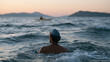 © forenna - Open water marathon swimmer alone mid-channel between two visible coastlines at dawn, silicone swim cap and goggles pushed up, treading water during a brief navigation check,