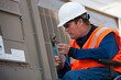 © Connect Images - Facilities engineer in a wheelchair opening inspection plate of commercial air conditioning system