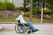 © Connect Images - Man with spinal cord injury in a wheelchair crossing at accessible street walk