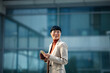 © Marko Geber - Smiling businesswoman with smartphone and coffee outside office
