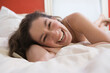 © Connect Images - Portrait of a mid adult woman lying on the bed and laughing