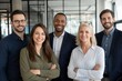 © Kevin - Diverse group of smiling business professionals standing together in a modern office setting.