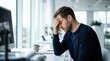 © Masque - Stressed man sitting at a desk holding his head to symbolize burnout and mental exhaustion.