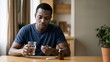 © ArtMajestic - African American man patient holding pill and glass of water at table. Healthcare and food poisoning recovery banner with copy space