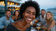 © Anastasiia Havelia - A realistic candid photo of a young woman in her mid-20s seated at the center of a rooftop bar table at sunset surrounded by four close friends, two male and two female, all clearl