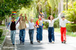 © Chaiphorn - Happy diverse LGBTQ friends holding hands running and celebrating with rainbow pride flags on a sunny park pathway during summer pride month festival