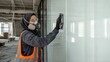 © Dmitry - Woman worker in hijab cleaning office glass wall. Professional cleaner with protective respirator and vest preparing construction site for handover. Industrial maintenance and service task.