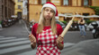 © Krakenimages.com - Woman in santa hat and gingham apron holds whisk and rolling pin, cheeks puffed in street; holiday frustration.
