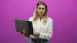 © Krakenimages.com - Blonde woman holds laptop with hands and types on keyboard while checking screen in studio; focus productivity.