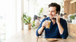 © Xenia - Smiling man talking on a smartphone and drinking iced coffee in a cafe. Adult male sitting by a window in a coffee shop. Leisure and communication concept