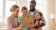 © SashaMagic - Diverse family holding cardboard house model, symbolizing homeownership and future dreams in a bright, modern living room