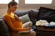 © Home-stock - Expectant mother sitting with baby clothes near open suitcase, writing preparation list