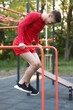 © New Africa - Athletic young man exercising on parallel bars at outdoor gym, low angle view