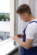 © New Africa - Professional worker with screwdriver installing window indoors