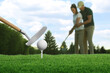 © New Africa - Golf ball, club and players on course, selective focus