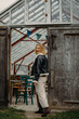 © Louise Forslycke Garbergs/Stocksy - Blond woman smiling entering rustic greenhouse building