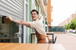 © AresStudio Belen y Carlos/Stocksy - Happy young man opening store shutter in morning