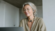 © Phirakhup - Senior woman with wearable health monitor and wireless earbud, calm indoor portrait