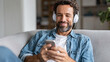 © Jane_S - Man listening with headphones and using smartphone at home