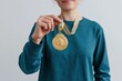 © Iryna - Close-up of person holding a gold first place medal for award celebration background and social media banner design