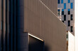 © yaqui_villegas - Metal facade shadows stretch through architecture, building lines, urban texture and business contrast along a dark exterior wall surface