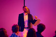 © Lustre Art Group  - Close speaker portrait during neon business seminar with audience foreground. Concept of keynote speech, executive coaching, communication training, leadership event and public speaking.