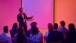 © Lustre Art Group  - Smiling male speaker presenting to audience beside blank screen in neon seminar room. Concept of keynote talk, business workshop, leadership training, corporate education and speaker engagement.