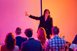 © Lustre Art Group  - Female presenter pointing at blank screen during business seminar. Concept of corporate workshop, team briefing, professional education, public speaking and visual presentation.