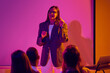 © Lustre Art Group  - Woman presenter making key point during colorful corporate training session. Concept of expert advice, business mentoring, communication skills, leadership lesson and audience engagement.