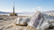 © Elena - Raw mineral crystal found at site of industrial lithium extraction. Close-up of lithium ore with drill rig in background. Natural resource exploration and mining industry concept.