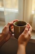 © Leonardo - Manos sosteniendo una taza cerca de la ventana