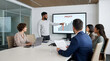© jack - Diverse business team having a meeting in a modern office while a male colleague points at a profit growth bar chart on a digital screen