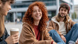 © pattozher - Friends Chatting Outdoors: A group of young adults with varied hair colors and styles share a lighthearted moment outdoors, one holding a coffee cup and smiling warmly.