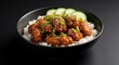 © Alfred - Close-up of saucy chicken pieces with sesame seeds, green onions, and cucumber on rice in a bowl