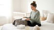 © Gophotograph - Pregnant woman packing a hospital bag on a bed in a nursery.
