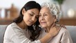 © ruangrit19 - A young woman embracing her elderly mother with love and care showing emotional support and a strong family bond in a bright living room.