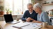 © Thiago - Happy senior couple reviewing financial documents and planning retirement at home